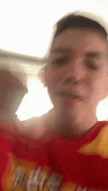 a blurry picture of a man wearing a red shirt with a yellow stripe on the sleeve