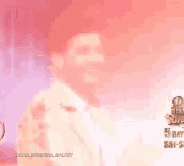 a man is smiling in front of a sign that says karan