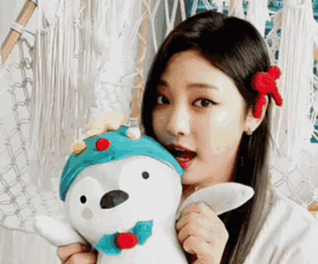 a woman is holding a stuffed animal with a penguin hat on .