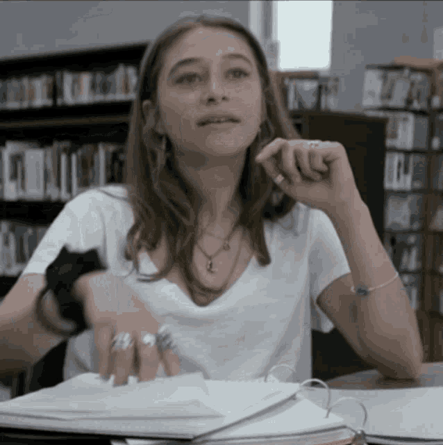 a girl with rings on her fingers sits at a table