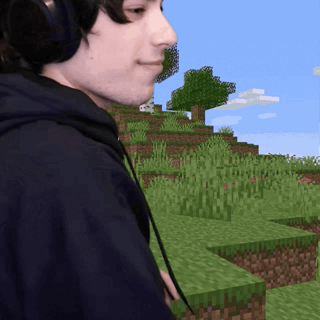 a man wearing headphones is standing in front of a minecraft world