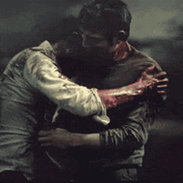 two men are hugging each other and one has blood on his neck