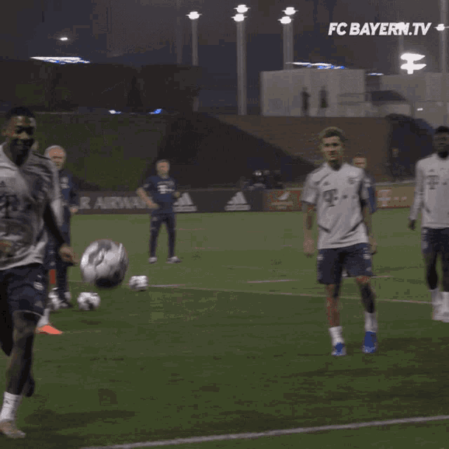 a group of soccer players on a field with fc bayern.tv written above them