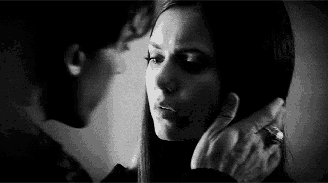 a black and white photo of a man holding a woman 's face .