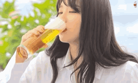 a woman is drinking a glass of beer outdoors .