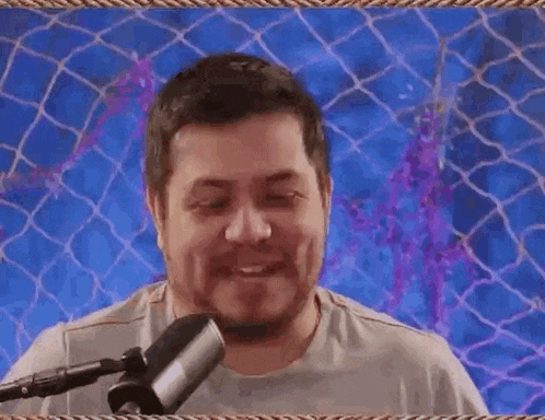a man is sitting in front of a microphone and making a face .
