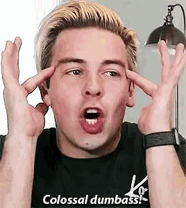 a man in a black shirt is making a funny face with his hands on his head .