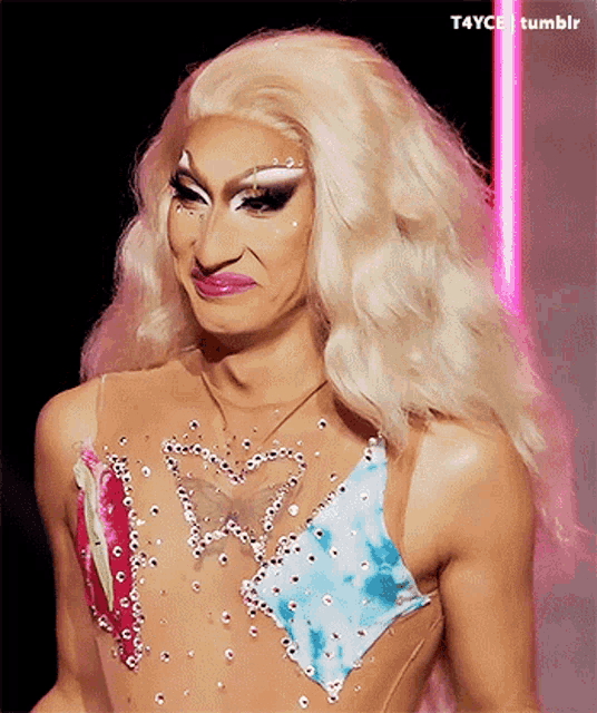 a drag queen with blonde hair and a butterfly on her chest is making a funny face