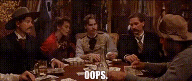 a group of men are sitting around a table playing cards with the words oops written on the table .