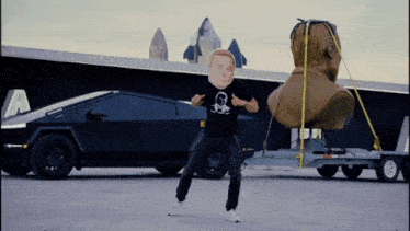 a man with a mask on his head stands in front of a black car
