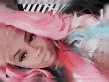 a woman with pink and blue hair is laying on a bed