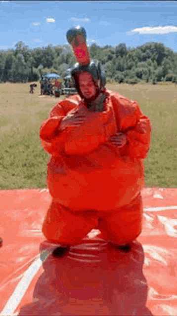 a man in an orange sumo wrestler costume is standing on a red mat