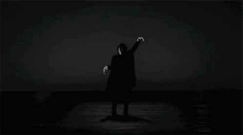 a man in a black coat is standing in the dark