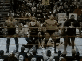 a group of wrestlers are standing in a ring with a crowd watching and a sign that says no smoking on it