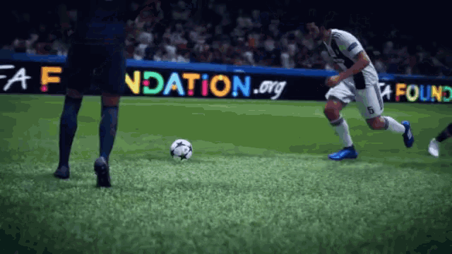 a soccer player kicks a ball in front of a sign that says foundation.org