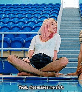 a woman with pink hair is sitting on the edge of a swimming pool with her legs crossed and says yeah that makes me sick