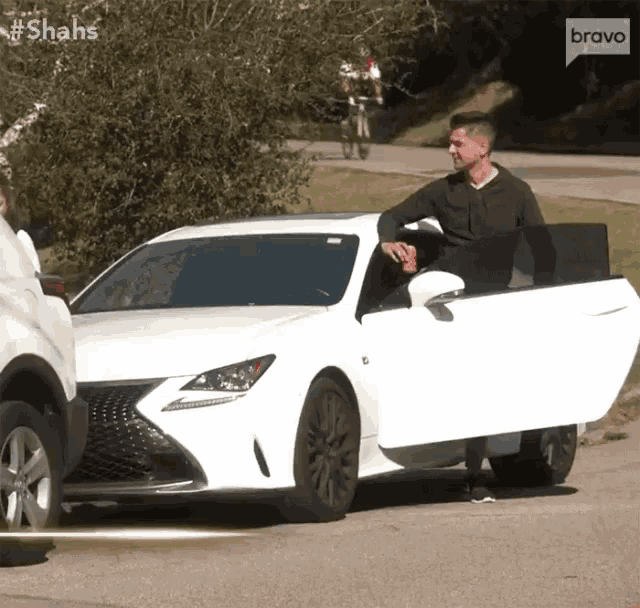 a man getting out of a white car with the bravo logo on the bottom