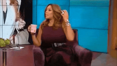a woman in a purple dress is sitting in a chair holding a cup of coffee