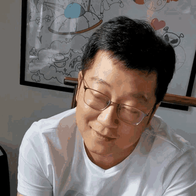 a man wearing glasses is smiling in front of a picture of a rocking horse