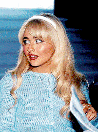 a blonde woman wearing a blue sweater and headband