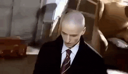 a bald man in a suit and tie is standing in front of a statue of a dog .