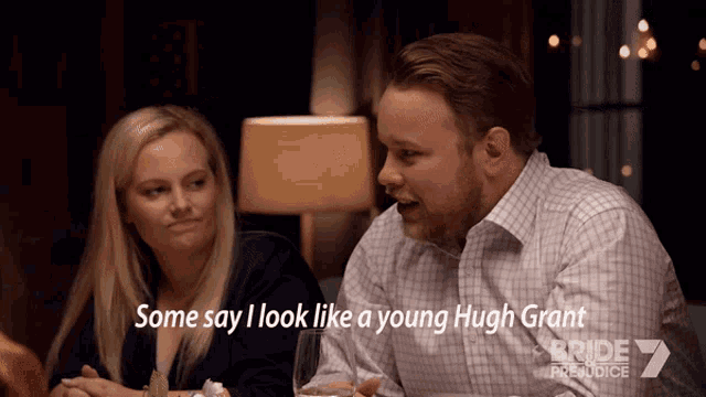a man and a woman are sitting at a table and the man says some say i look like a young hugh grant