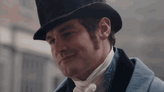 a man wearing a top hat and a blue jacket smiles