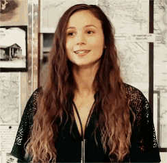 a woman with long brown hair is wearing a green lace shirt