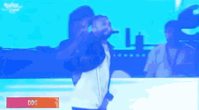 a man with a beard is singing into a microphone on a stage in front of a blue background .