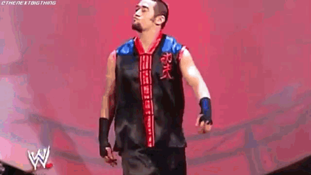 a man in a black and red shirt is standing on a stage .