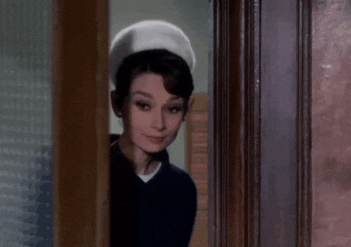 a woman is standing in a doorway wearing a white hat and a blue shirt .