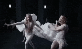 a group of people are dancing on a stage in white clothes .