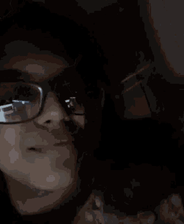 a man wearing glasses covering his mouth with his hand