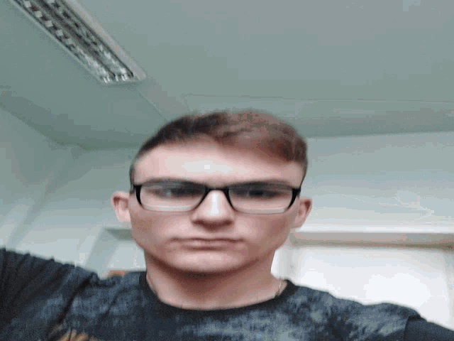 a man wearing glasses and a black shirt looks down