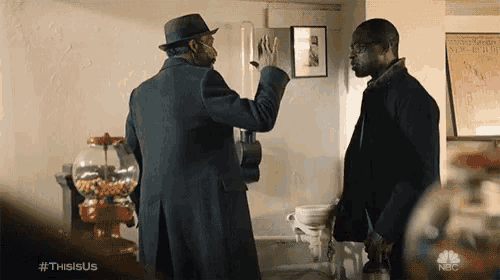 two men are standing next to each other in a room with a gumball machine in the background .