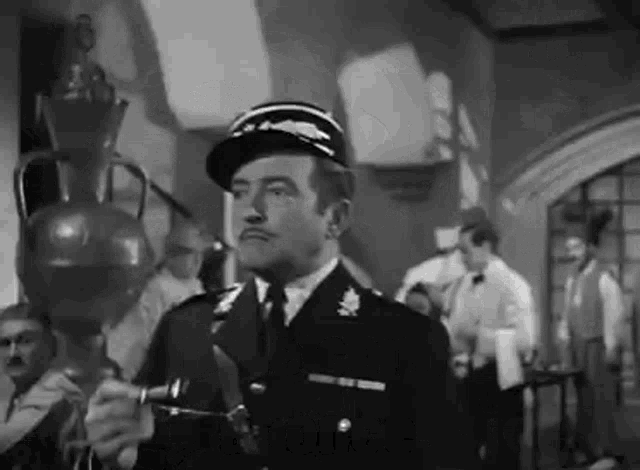 a man in a military uniform is standing in a room holding a bottle .