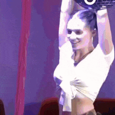 a woman in a white crop top is holding a dumbbell over her head with the letter o on it