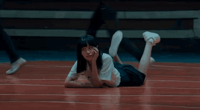 a girl is laying on her stomach on the floor of a gym .