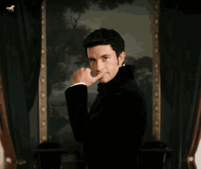 a man in a black suit is standing in front of a large painting