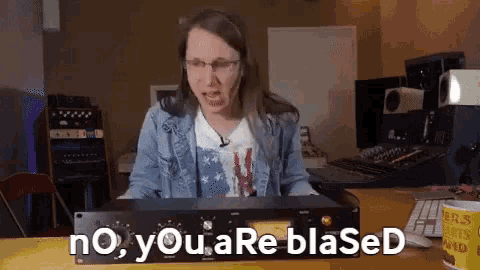 a woman sitting at a desk with a device that says no you are blased on it
