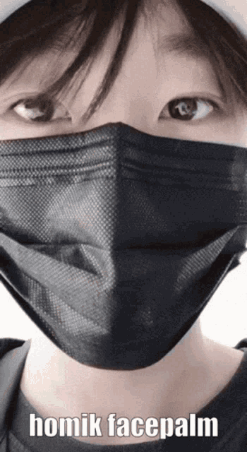 a close up of a person wearing a black face mask with the words homik facepalm below it