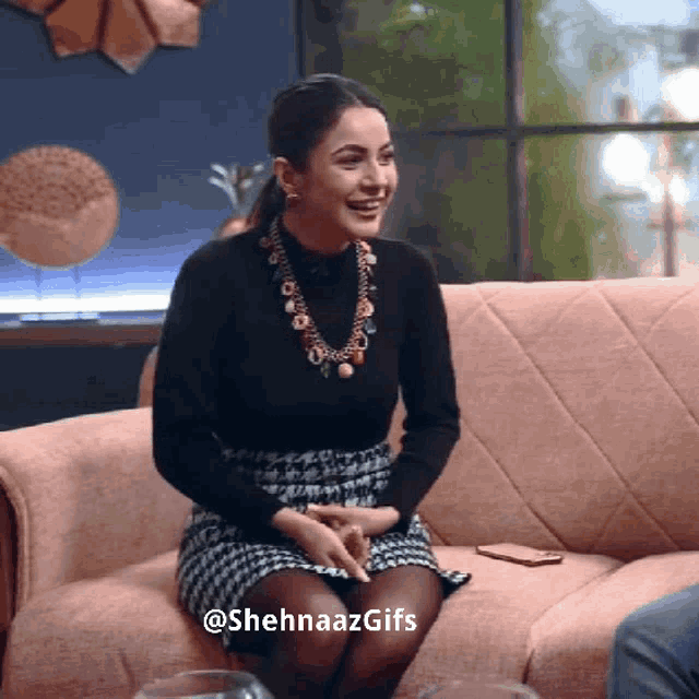 a woman is sitting on a couch wearing a black top and a skirt