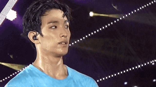 a man in a blue shirt wipes his sweat off his forehead