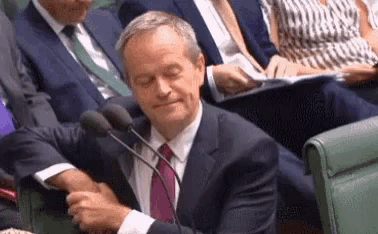 a man in a suit and tie is sitting in front of a microphone in a room .