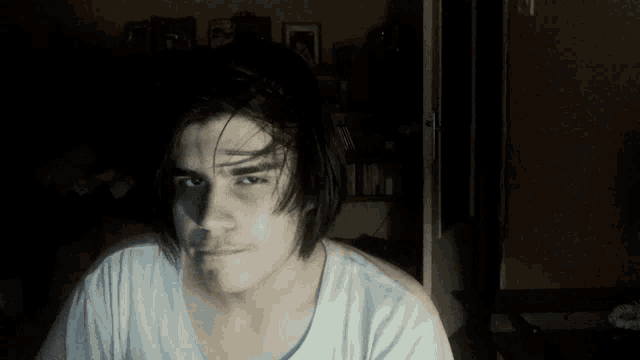 a young man with long black hair is making a funny face
