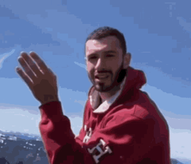 a man wearing a red sweatshirt with the letter h on it