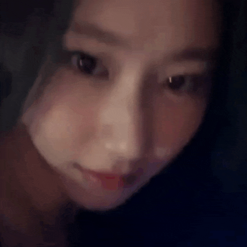 a close up of a woman 's face looking at the camera in a dark room .