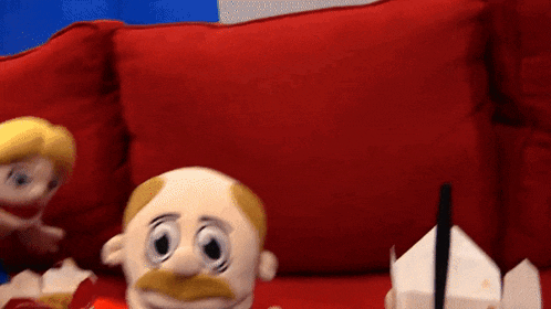 a stuffed cartoon character with a mustache is sitting on a red couch