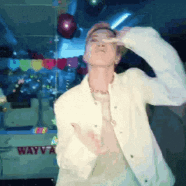 a man in a white jacket is dancing in front of a sign that says wayv a