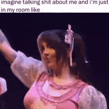 a woman in a pink dress is dancing on a stage with her arms outstretched .